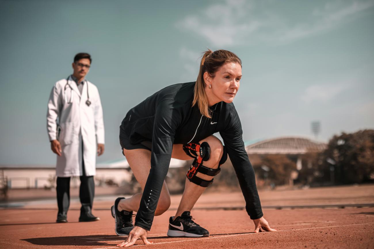 Personne s'aprêtant à faire un sprint, un médecin derrière elle